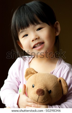 Smiling little child holding a teddy bear in her hand