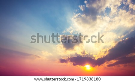 red purple with orange sunset in overcast blue sky with sun rays light