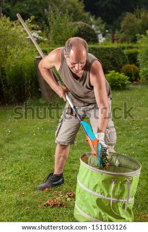 The gardener is filling the trash with some leaves.