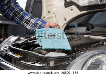 A car mechanic checks the oil level in a car engine during routine maintenance.