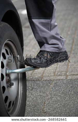 A mechanic tries to unscrew the tire screws with the foot to do a tire change.