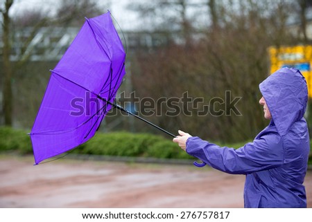 A woman is holding an umbrella in the wind.