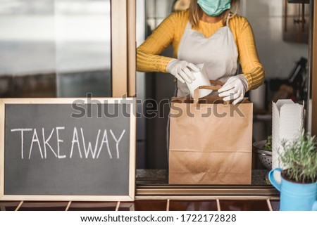 Young woman preparing takeaway organic food inside plastic free restaurant during Coronavirus outbreak time - Worker inside kitchen cooking food for online delivery service - Focus on right hand