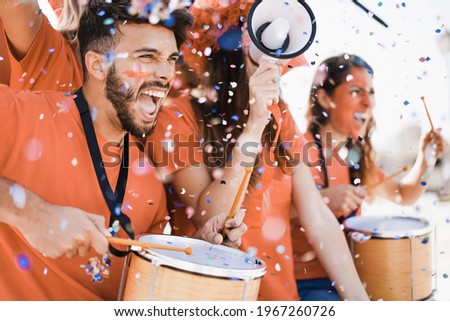 Orange sport fans screaming while supporting their team out of the stadium - Football supporters having fun at competion event - Focus on man face