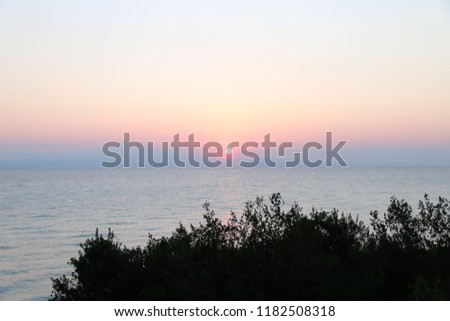 Amazing sunrise at Mediterranean sea in Greece. Colorful view at early summer morning sun trought coast trees.
