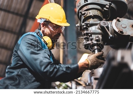 Factory male worker. Engineer man worker in plant production drilling at machine in smart factory wearing yellow hard hat safety first at mechanic factory. Foto stock © 