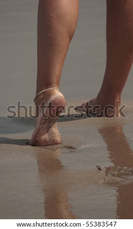 Beautiful female feet going on an ocean beach