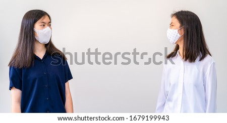 Young Asian women, wearing mask, standing safe distant apart while talking to each other - safety practice during COVID-19 virus outbreak ストックフォト © 