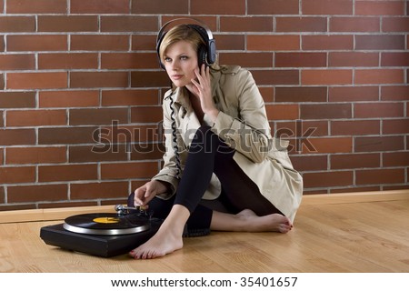 young women in a trenchcoat listens to music of a record player