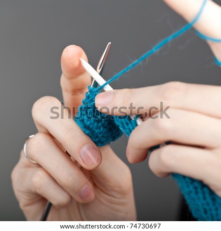 Hands of a young woman knitting with blue wool