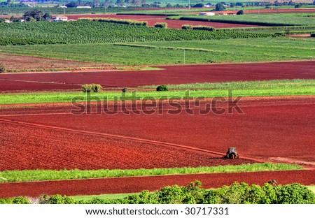A lone tractor ploughs the red earth on a farm near Bundaberg, Queensland, Australia