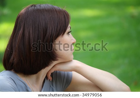 Profile of a girl sitting in the city park on the bench