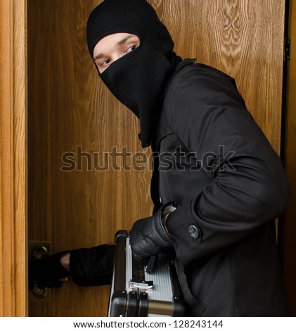 Male burglar stealing case with money