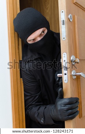 Male burglar in mask breaking into the house