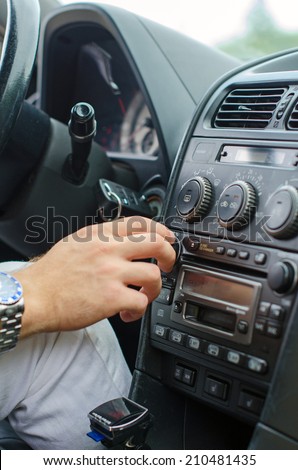 Man\'s hand tuning radio in the car.