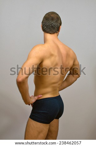 Muscular male model posing. Back view.