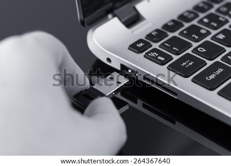 Hand plugging usb flash drive to laptop. Black and white photo.