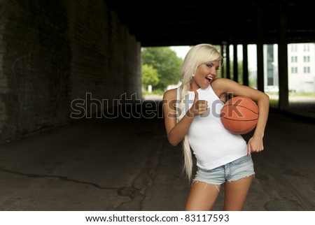 beautiful smiling girl standing with a basketball in the street, thumbs up