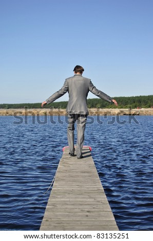 man in a gray suit walking on the pier, from the back