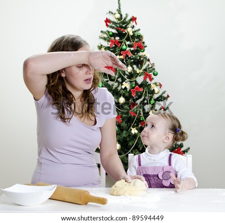 little girl and mother are preparing Christmas cookies, Mom seems to be tired