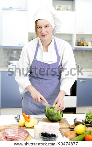 Attractive chief cook preparing food, cuts broccoli