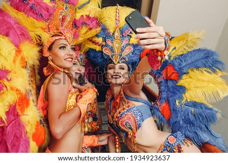 Woman in brazilian samba carnival costume with colorful feathers plumage with mobile phone take selfie in old entrance with big window Foto stock © 