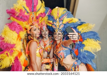 Woman in brazilian samba carnival costume with colorful feathers plumage with mobile phone take selfie in old entrance with big window. Foto stock © 