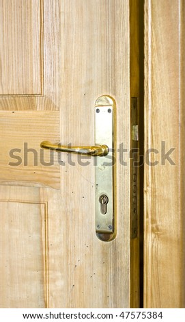 Golden door handle and keyhole on the brown wooden door.