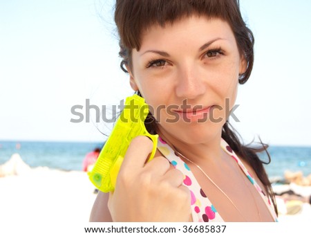 beautiful woman on a beach with yellow toy water gun