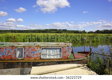 a weathered narrow boat on a river on a beautiful summers day