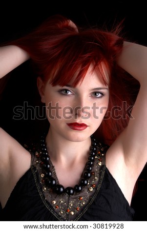pretty red head girl holding her hands above the head, isolated on black background
