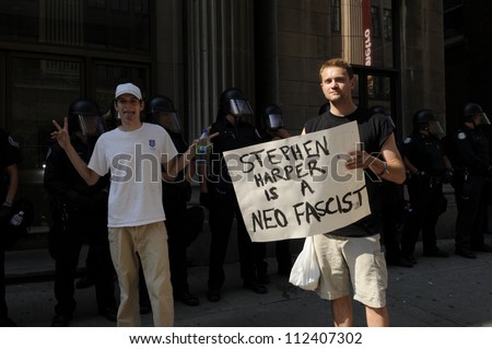 TORONTO-JUNE 25:  A protester holding a banner saying the Prime Minister of Canada is a fascist while another one makes  a funny face during the G20 Protest on June 25, 2010 in Toronto, Canada.