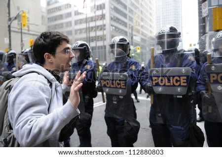 TORONTO-JUNE 26:  A protester raising his hands so as to prove his innocence in front of the riot police during the G20 Protest on June 26, 2010 in Toronto, Canada.