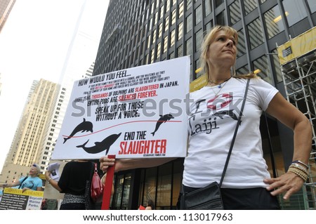 TORONTO-AUGUST 31: An activist with a  sign which tells the story of Taiji  during a rally to protest the start of the annual  dolphin hunt at Taiji,Japan on August  31, 2012 in Toronto, Canada.