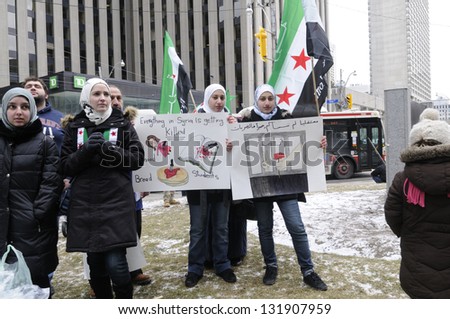 TORONTO-MARCH 16: Syrian teens holding banners during a protest rally organized to raise awareness and commemorate two years of Syrian revolution on March 16, 2013 in Toronto, Canada.