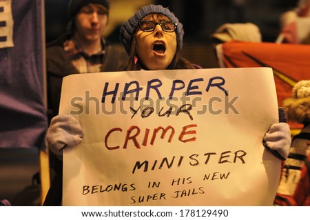 TORONTO-FEBRUARY 8: Woman with a sign saying the PM as a crime minister during a protest in front of the Metro Convention Centre while Mr.Harper was inside  on February  8 ,2014 in Toronto,Canada.