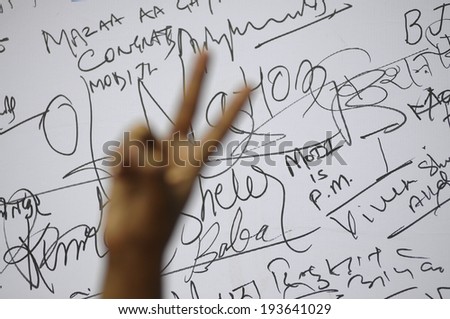 NEW DELHI-MAY 16:  A BJP supporter showing victory sign  in front of a message board to write best wishes for Mr. Modi after wining the Indian National election on May 16, 2014 in New Delhi , India.