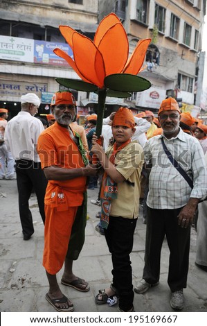 VARANASI - MAY 6:  A BJP supporter holding a huge replica of Lotus flower- emblem of BJP during a road show on May 6, 2014 in Varanasi , India.