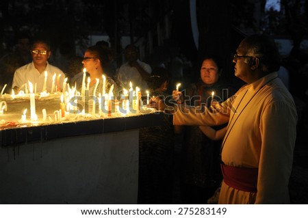 KOLKATA - MARCH 16 :  A Christian priest lighting candles during a candle light vigil to protest gang rape of an elderly nun on March 16, 2015 at Allen Park in Kolkata, India.