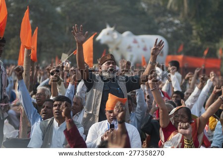 KOLKATA - DECEMBER 20:  A man chanting songs  with a dummy cow in the background during the Golden Jubilee celebration of VHP - a Hindu nationalist organization on December 20, 2014 in Kolkata,India.