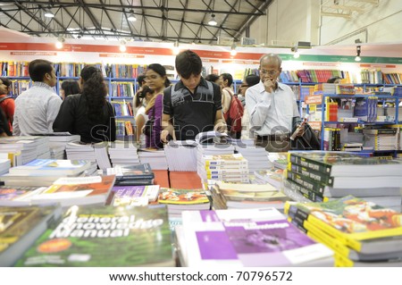 KOLKATA- FEBRUARY 4: A young guy flips though a book and an old man looking at it ,during the 2011 Kolkata Book fair in Kolkata, India on February 4, 2011.
