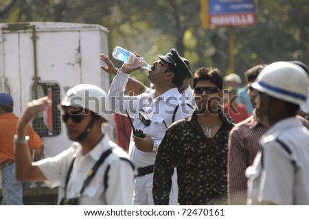 KOLKATA- FEBRUARY 13: A thirsty traffic police constable drinking some water on a hot and humid day  during a political rally  in Kolkata, India on February 13, 2011.