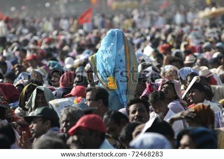 KOLKATA- FEBRUARY 13:   An old Indian wman makes her way through the crowd during a political rally  in Kolkata, India on February 13, 2011.