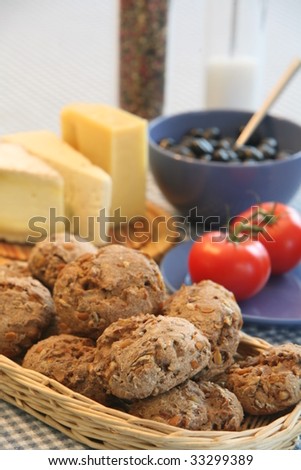 Freshly-baked whole-grain rolls, ripe tomatoes, cheeses, bowl of kalamata olives, and salt and pepper grinders