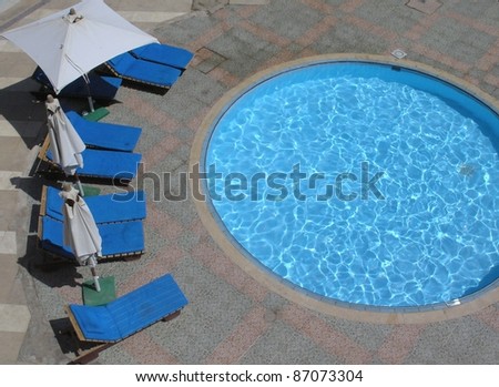 empty pool chairs around circular pool