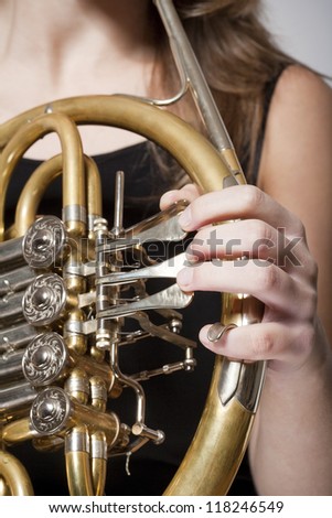 detail of a female musicians fingers playing concert french horn