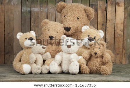 a group of cute teddy bears sitting together against an old wooden wall