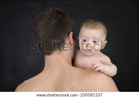 father with baby looking over his shoulder, on black