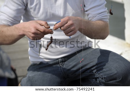 Closeup on hands putting worm on fishing hook