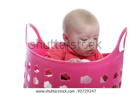 baby playing in a pink plastic laundry basket